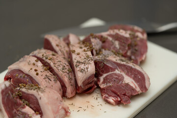 Close-up raw lamb meat chops seasoned herbs white cutting board