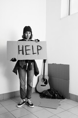Mature homeless woman holding cardboard with word HELP indoors