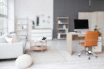 Blurred view of office with interior designer's workplace and sofa