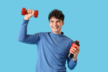 Sporty young man with protein shake and dumbbell on blue background