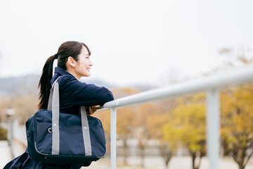 Obraz premium 下校・通学・登校中に待ち合わせ・景色を眺める制服姿の女子高校生・女子高生・女子中学生 