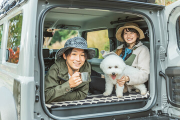 犬・ペットを連れてドライブ・デイキャンプ・キャンプ・車中泊する若いアジア人カップル・夫婦・キャンパー
