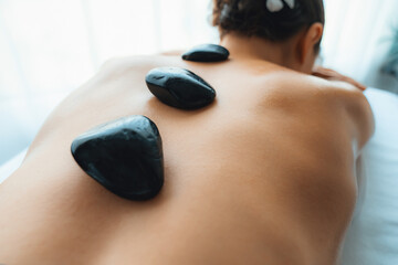 Hot stone massage at spa salon in luxury resort with day light serenity ambient, blissful woman...