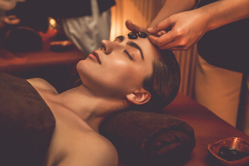 Caucasian couple enjoying relaxing anti-stress head massage with hot stone and pampering facial...