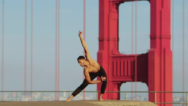 Male ballet dancer doing a choreographic dance move in front of the  of the Golden Gate Bridge in San Francisco, California, USA
