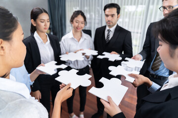 Multiethnic business people holding jigsaw pieces and merge them together as effective solution...