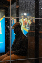 Man waiting at a bus stop in the rain