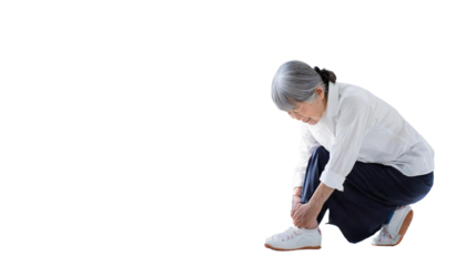 足首を押さえてしゃがみこむ高齢女性