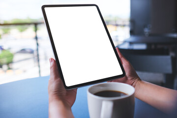 Mockup image of a woman holding digital tablet with blank white desktop screen in cafe