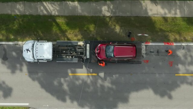 Car crash site with tow truck loading destroyed vehicle on American street. Emergency services personnel responding to accident in Florida, USA.