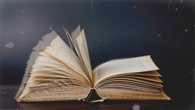 Close up studio shot of old retro hardcover book on dark background in warm light. Old vintage book laying,wind turning pages.
