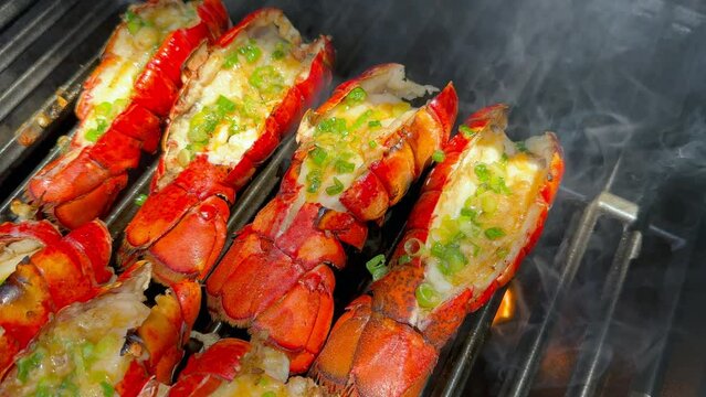 Grilled Lobster Tails with Garlic Lemon Butter Sauce Topped with Green Onions. Closeup During Grilling. Summer Seafood Barbecue