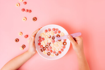 Breakfast of corn rings with milk on pink background.