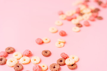 Breakfast cereals in the shape of rings on a pink background.