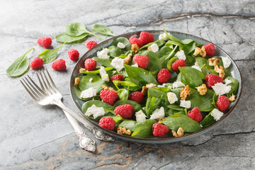 Baby spinach with raspberries, feta and walnuts close-up in a plate on the table. Horizontal