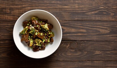 Beef with broccoli in bowl over wooden background