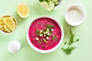 Cold summer beetroot soup in bowl over green background