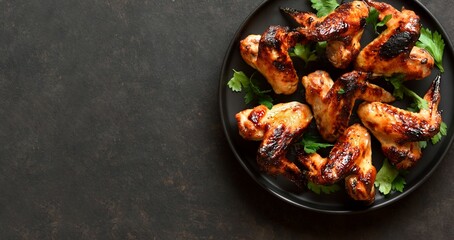 Bbq chicken wings on plate over dark stone background