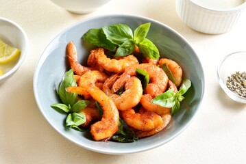 Roasted prawn with basil leaves in bowl on light stone background