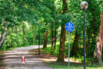 City park entrance. Foot and bicycle path sign. Natural greenery rest.