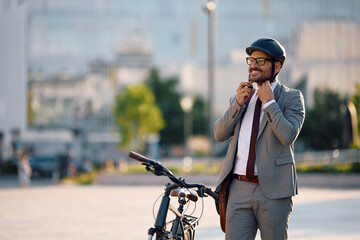 Happy businessman adjusting cycling helmet on  street.