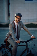 Happy businessman riding bicycle and looking at camera.