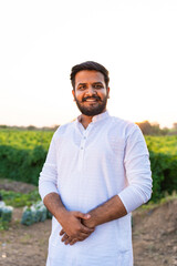 young Indian farmer standing at agriculture field confidently