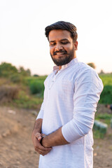 Young indian farmer standing at agriculture field 