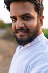 Fototapeta premium Young indian farmer standing at agriculture field 