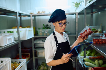Female cook checking kitchen's supplies while working in  restaurant.