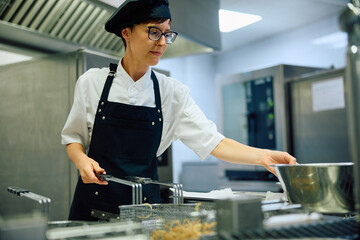 Female chef preparing  meal while working in restaurant.