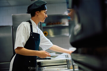 Female chef frying food while working in kitchen.