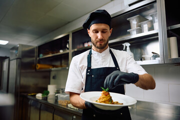 Male chef finishing  dish while cooking in restaurant.