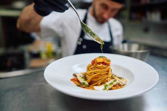 Close up of chef finishing dish before serving it to a guest in restaurant.