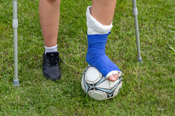 Boy with a broken leg in a cast during a football match an injury to a young athlete