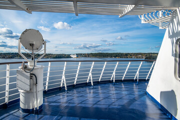 Searchlight on ship deck against view to Sweden shores and cruise ship on far.