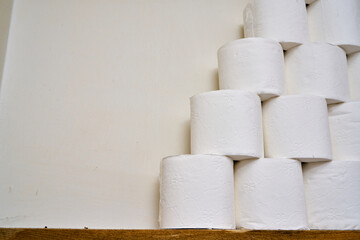 White classic toilet papers on a wooden shelf in a bathroom.