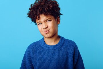 playful young african american boy expressing joy with a silly face against a vibrant blue background