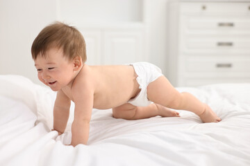 Happy baby boy crawling on bed at home