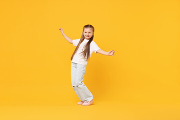 Cute little girl dancing on yellow background, space for text