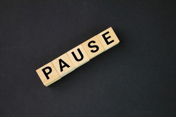 wooden arrangement with the word pause. the concept of pausing or having to stop.