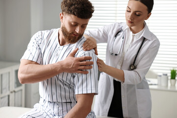 Obraz premium Sports injury. Doctor examining patient's shoulder in hospital