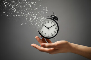 Time running out. Woman with dissolving alarm clock on grey background, closeup