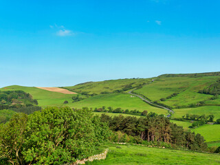 An overview of Abbotsbury village and surrounding fields and Chesil beach from St Catherine`s Hill in Dorset on a sunny morning in May