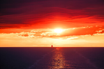 A large ship silhouetted on the horizon of the Mediterranean sea against a dramatic orange sunset