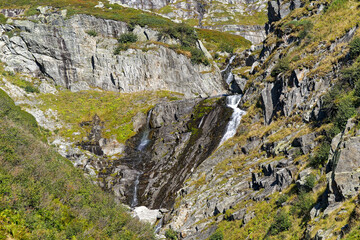Alpine landscape with rocks and grass at Swiss mountain pass St. Gotthard on a sunny late summer day. Photo taken September 10th, 2023, Gotthard, Switzerland.