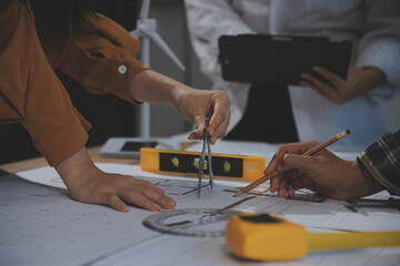 Team of multiethnic architects working on construction plans in meeting room. Engineers discussing on project in office. Mature businessman and woman standing around table working on blueprint.