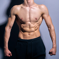 Fototapeta premium A topless male, fit, muscled. and athletic teenager fitness model lifting weights in a gym.