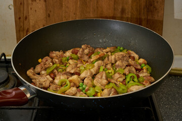 Chinese fried chicken with vegetables in wok frying pan