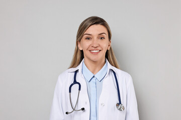 Portrait of happy doctor with stethoscope on light grey background